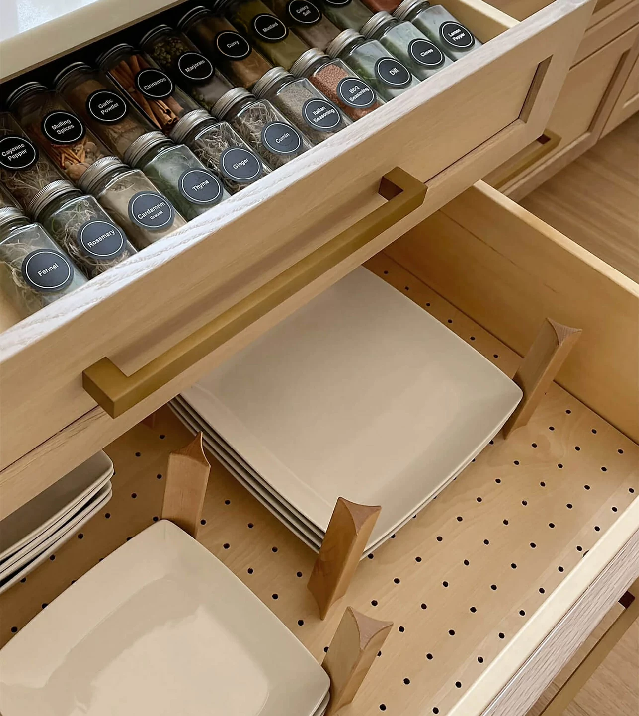 A wide drawer with a spice rack drawer above a deep kitchen drawer with a peg system organizer for plate and bowl storage.