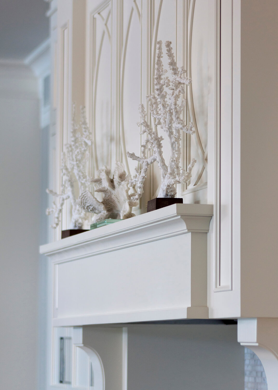 A white wood hood with a mantel shelf displaying Coastal style decor and coral.
