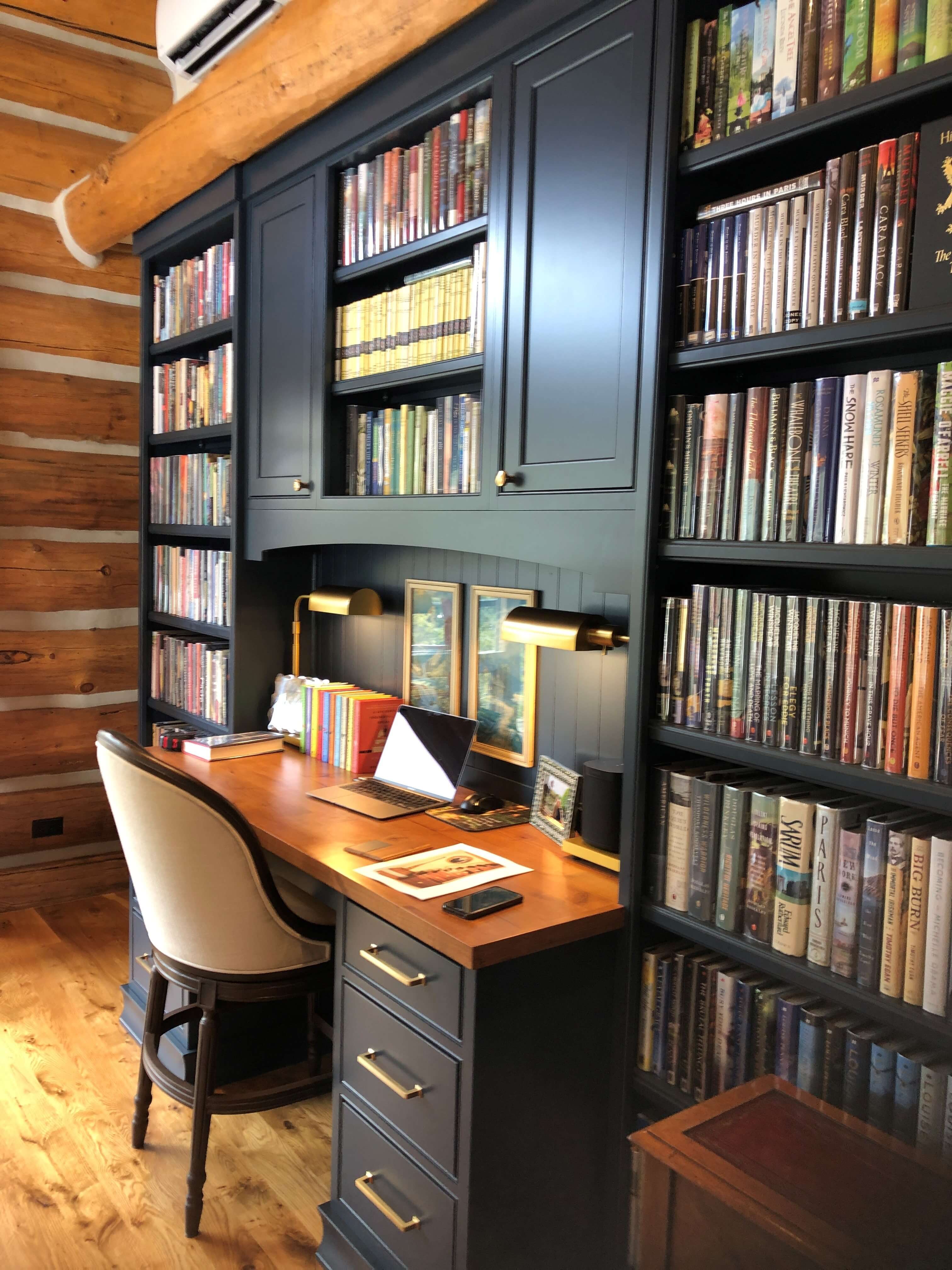 A traditional home office design with dark painted custom office cabinets and desk.