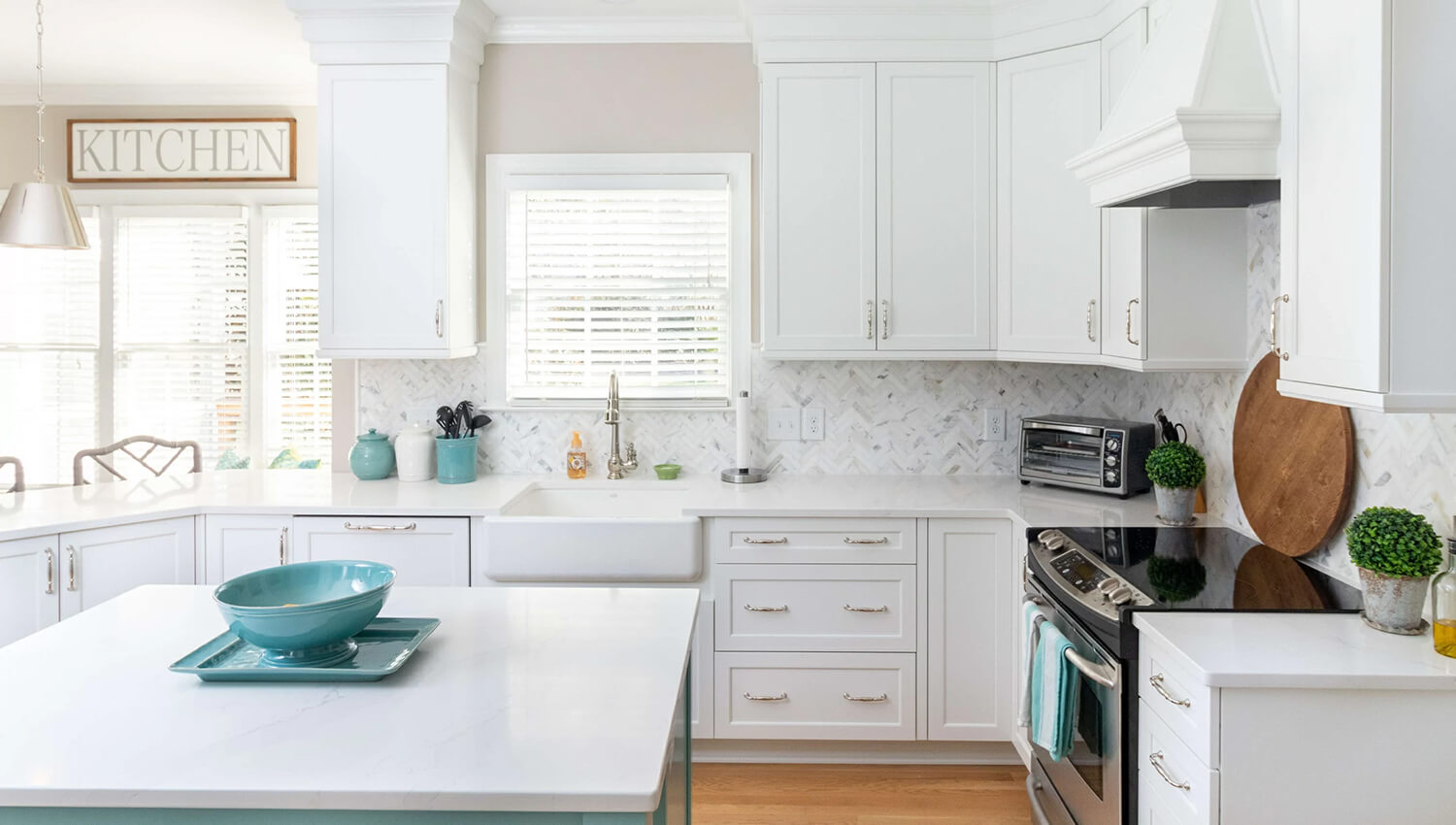 A white and ocean blue coastal kitchen design with white painted cabinets and a light blue painted kitchen island.