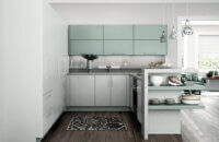 A sleek and modern two-toned kitchen with soft off-white, gray matte cabinets paired with light minty green cabinets with simplistic slab cabinet doors.