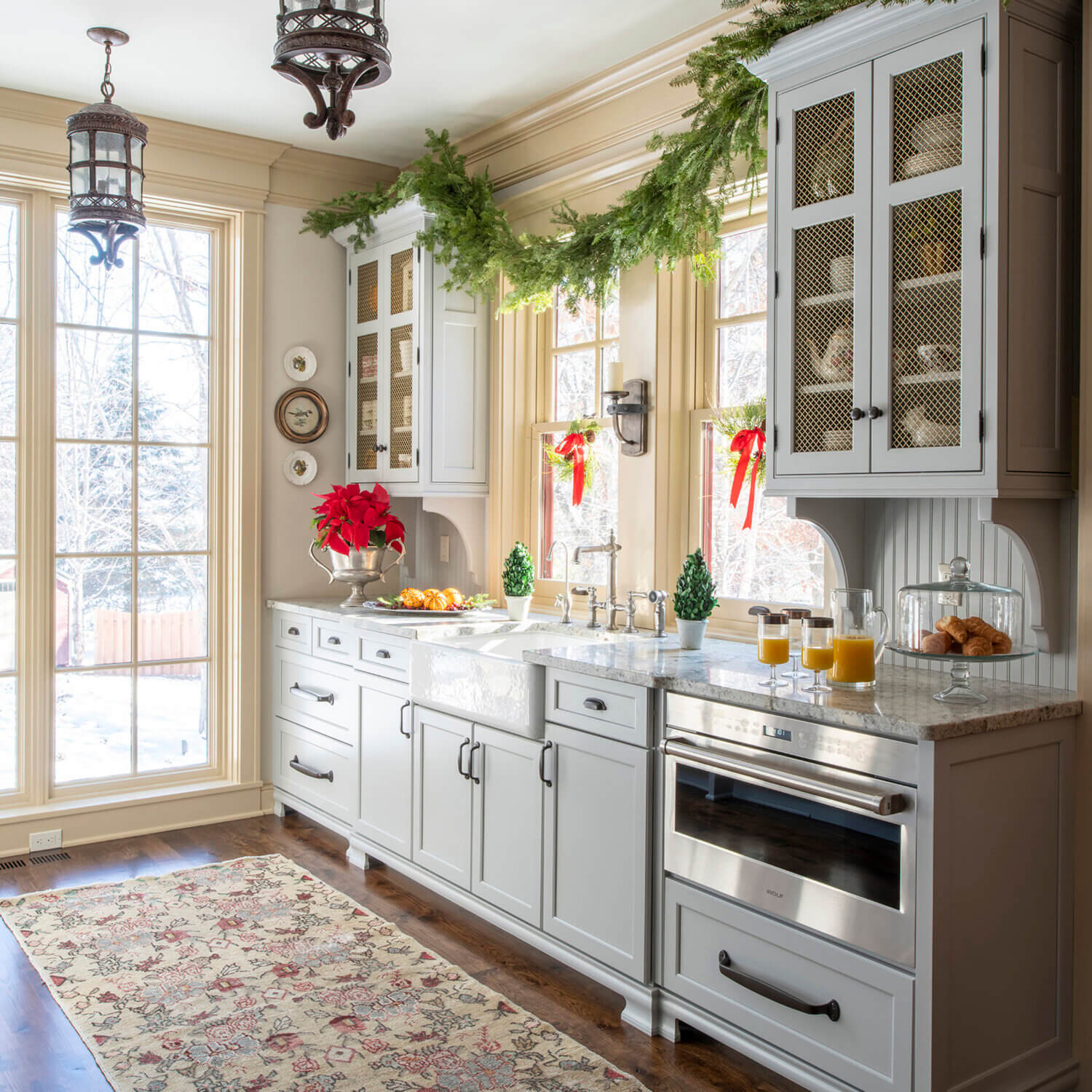 The modern old English style butler's pantry with light gray painted cabinets from Dura Supreme is decorated for Christmas.