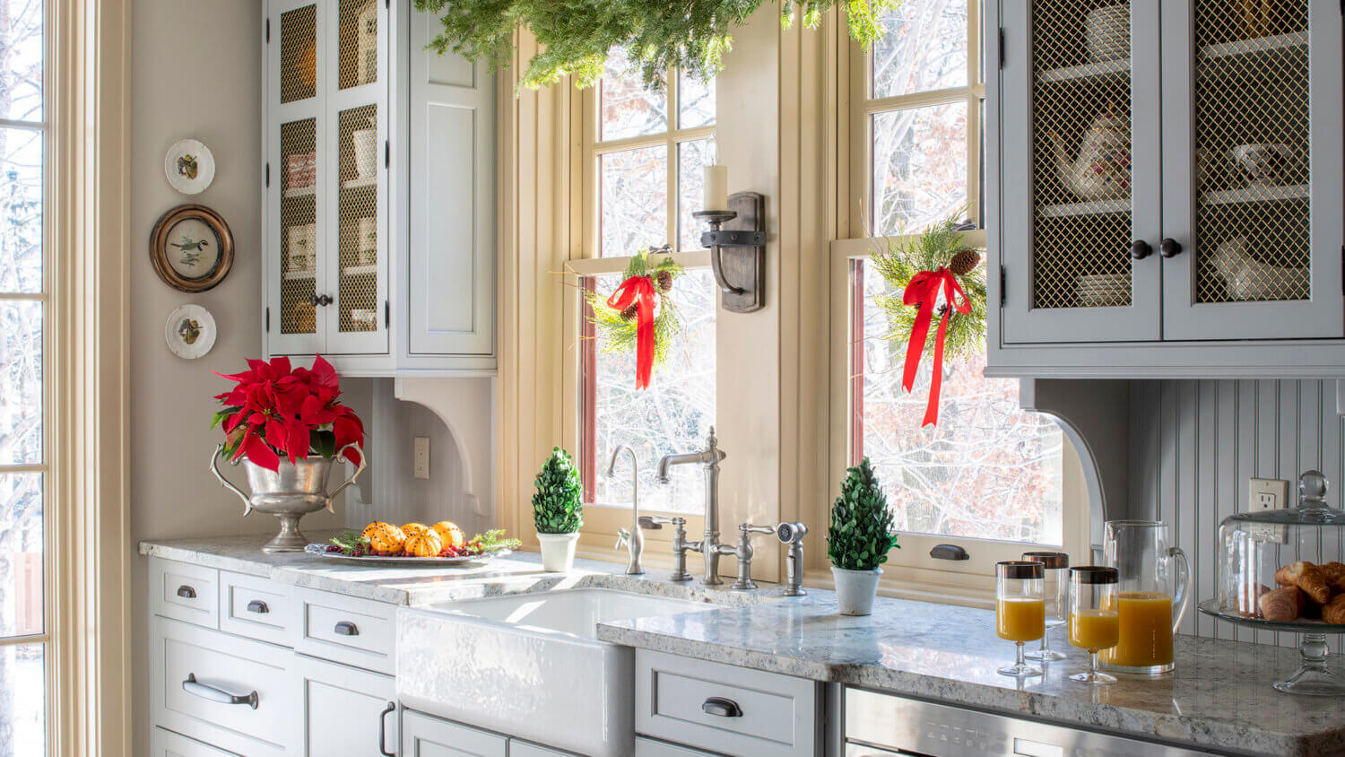 A Christmas kitchen design with an old English style featuring light gray painted cabinets from Dura Supreme Cabinetry.