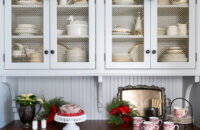 A Christmas kitchen with light gray painted cabinets, a wood countertop, furniture style details, and pretty holiday decor.
