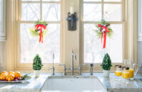 This kitchen sink window view is decorated for the holidays with garlands and mini wreaths.