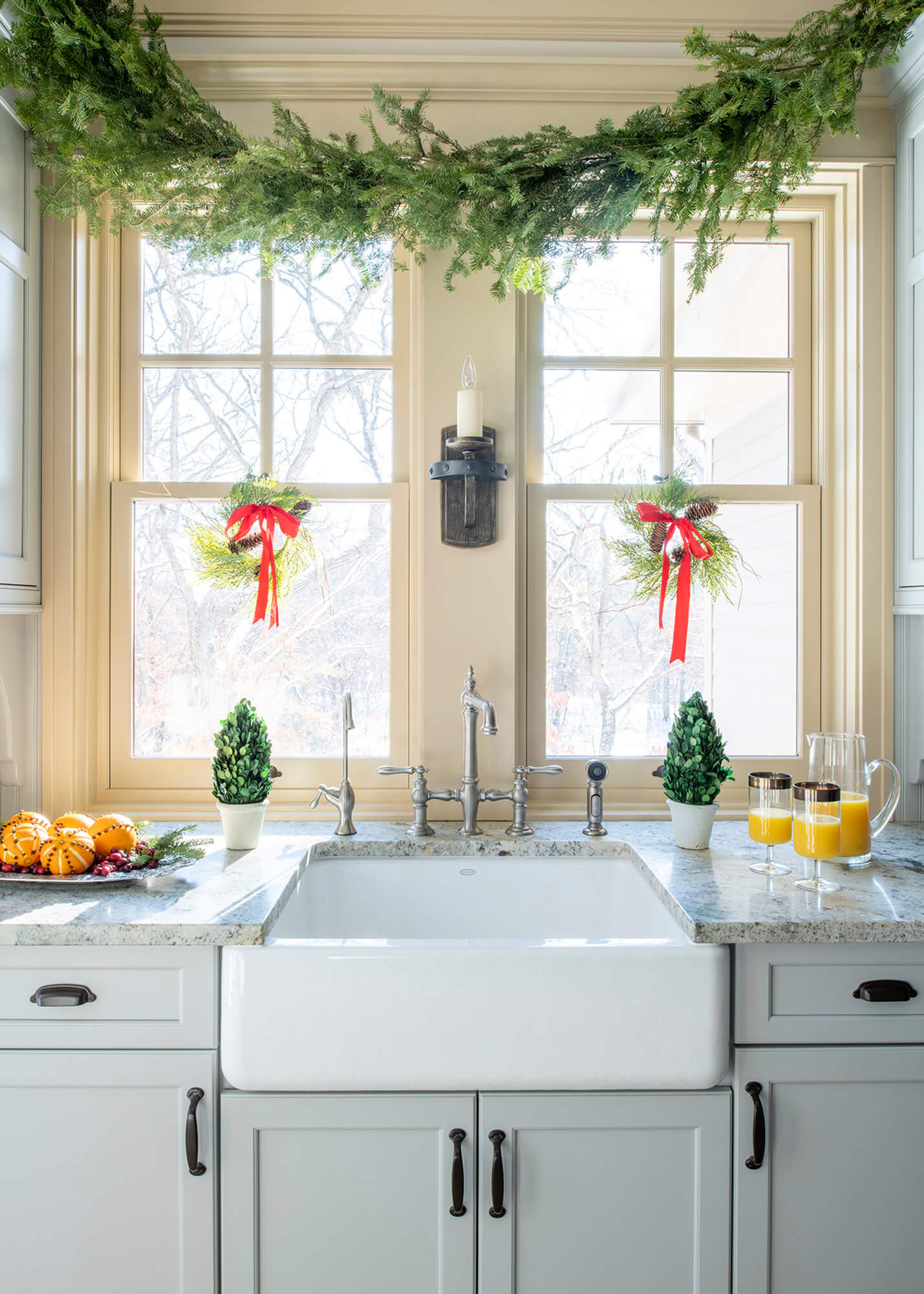 This kitchen sink window view is decorated for the holidays with garlands and mini wreaths.