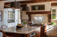 A traditional English styled kitchen with a messy kitchen to the side with a modern English style and light gray painted cabinets.