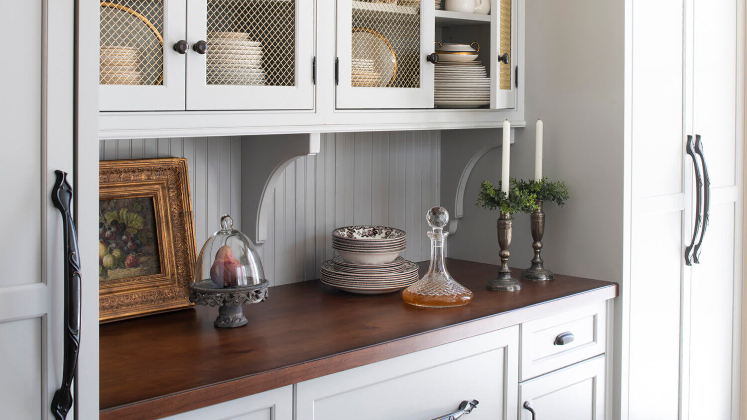A wood top countertop with bead board backsplash, corbels brackets, and inset wall cabinets to create a furniture style built-in hutch look.