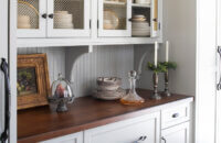 A wood top countertop with bead board backsplash, corbels brackets, and inset wall cabinets to create a furniture style built-in hutch look.