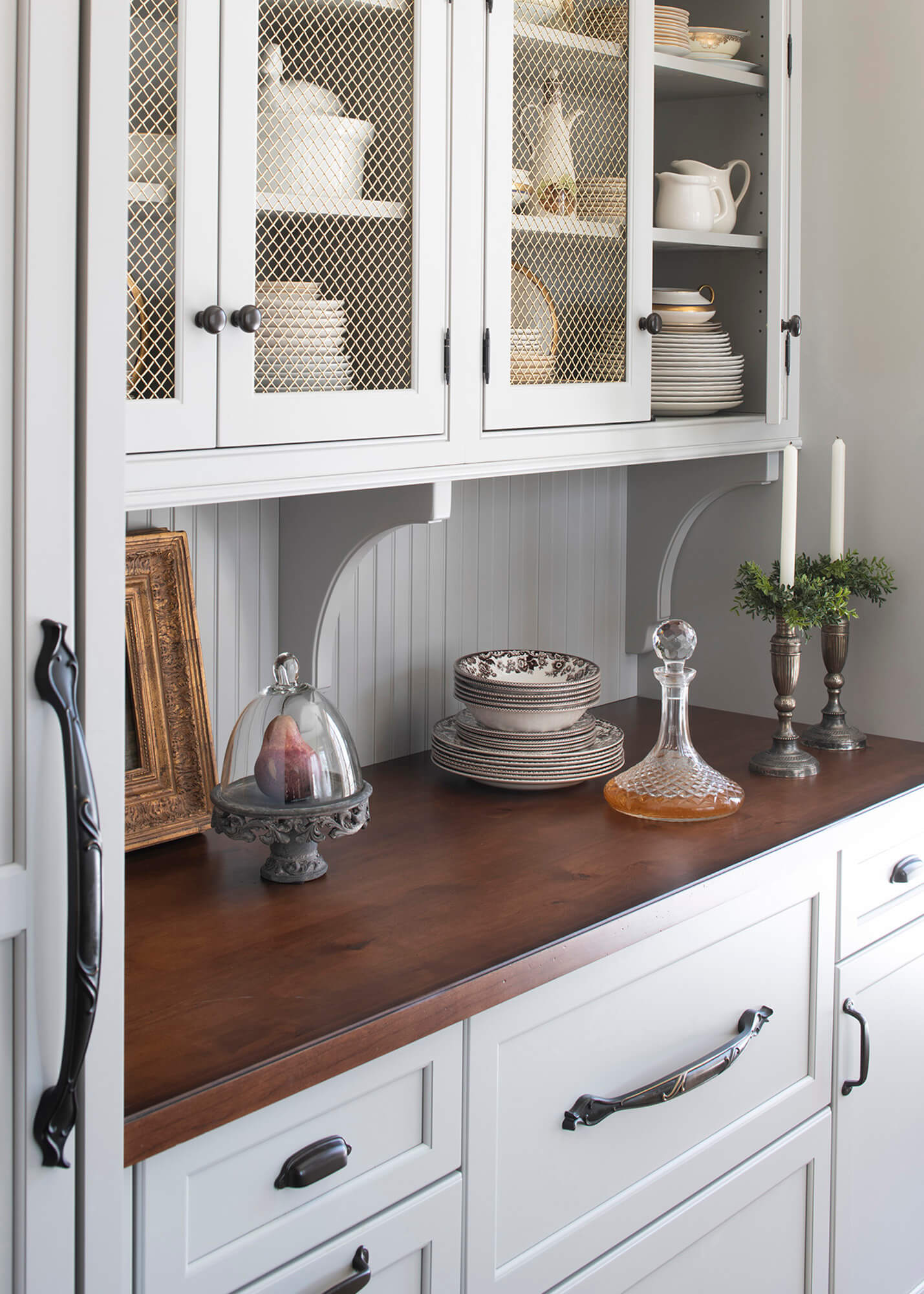 Gray painted inset cabinets with brushed brass wire mesh inserts decorative corbels and beadboard backsplash,