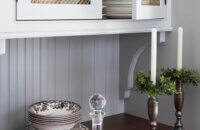 Inset cabinet doors with a gold wire mesh insert for storing decorative plateware and dishes.