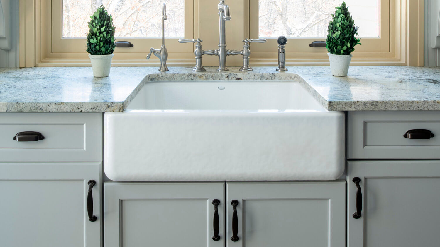 A classic white apron sink with light gray painted cabinets and countertops.
