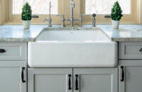 A classic white apron sink with light gray painted cabinets and countertops.
