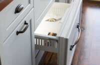 An ice drawer hidden behind cabinet appliance panel doors in an old English style butler's pantry.
