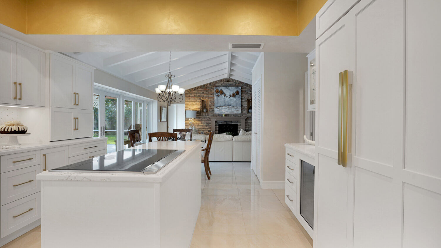 This bright white kitchen features Dura Supreme Cabinetry’s Homestead Panel door style in “White” paint paired with white countertops & backsplash with a golden ceiling and gold hardware pulls.