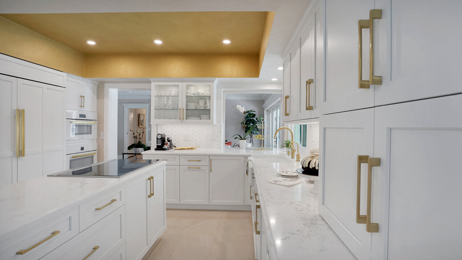 This bright white kitchen features Dura Supreme Cabinetry’s Homestead Panel door style in “White” paint paired with white countertops & backsplash with a golden ceiling and gold hardware pulls.