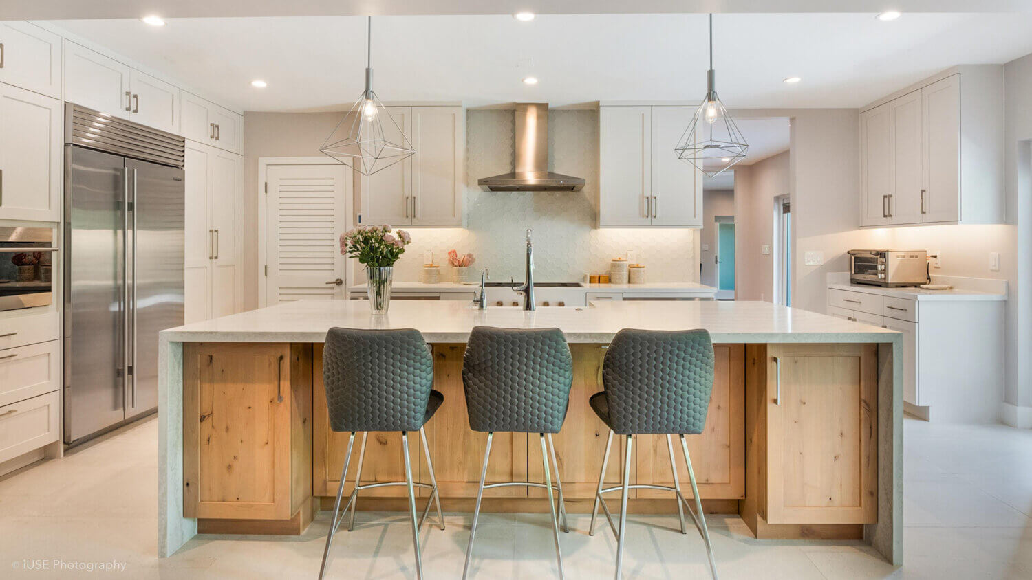 Modern, crisp paint finishes collide with natural, rustic, knotty alder in this transitional style kitchen remodel. The kitchen cabinets use Dura Supreme Cabinetry’s Hudson door style in Knotty Alder with a “Natural” finish for the kitchen island contrasted with the “Dove” paint for the perimeter.