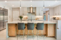 Modern, crisp paint finishes collide with natural, rustic, knotty alder in this transitional style kitchen remodel. The kitchen cabinets use Dura Supreme Cabinetry’s Hudson door style in Knotty Alder with a “Natural” finish for the kitchen island contrasted with the “Dove” paint for the perimeter.