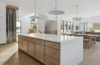 A view over the beautiful quarter-sawn white oak kitchen island with a light stained cabinet finish and white quartz countertops with waterfall ends.