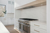 A trendy range alcove design with white cabinets and a light wood frieze accent on the wood hood.