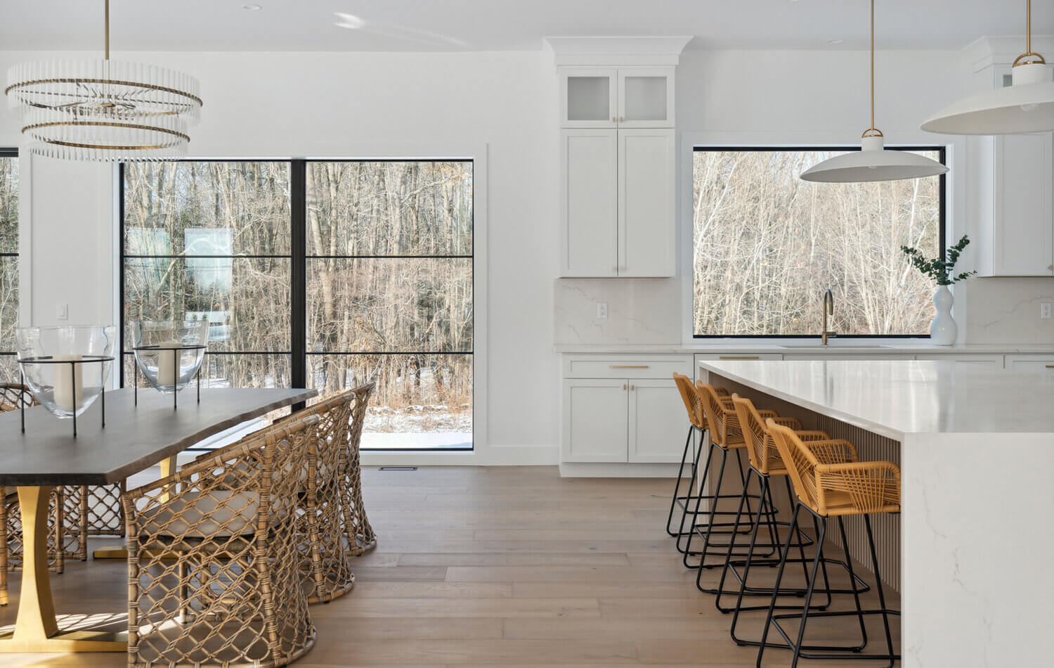 A stunning modern farmhouse kitchen with a wide range alcove space with a simple raw-wood panel mantel over the range. The island features custom fluted details to accent the seating area while waterfall countertops frame the island.