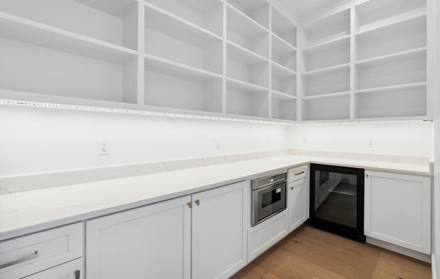 The walk in pantry is all white with open wall cabinet shelves for easy access and checking inventory of kitchen goods and supplies.