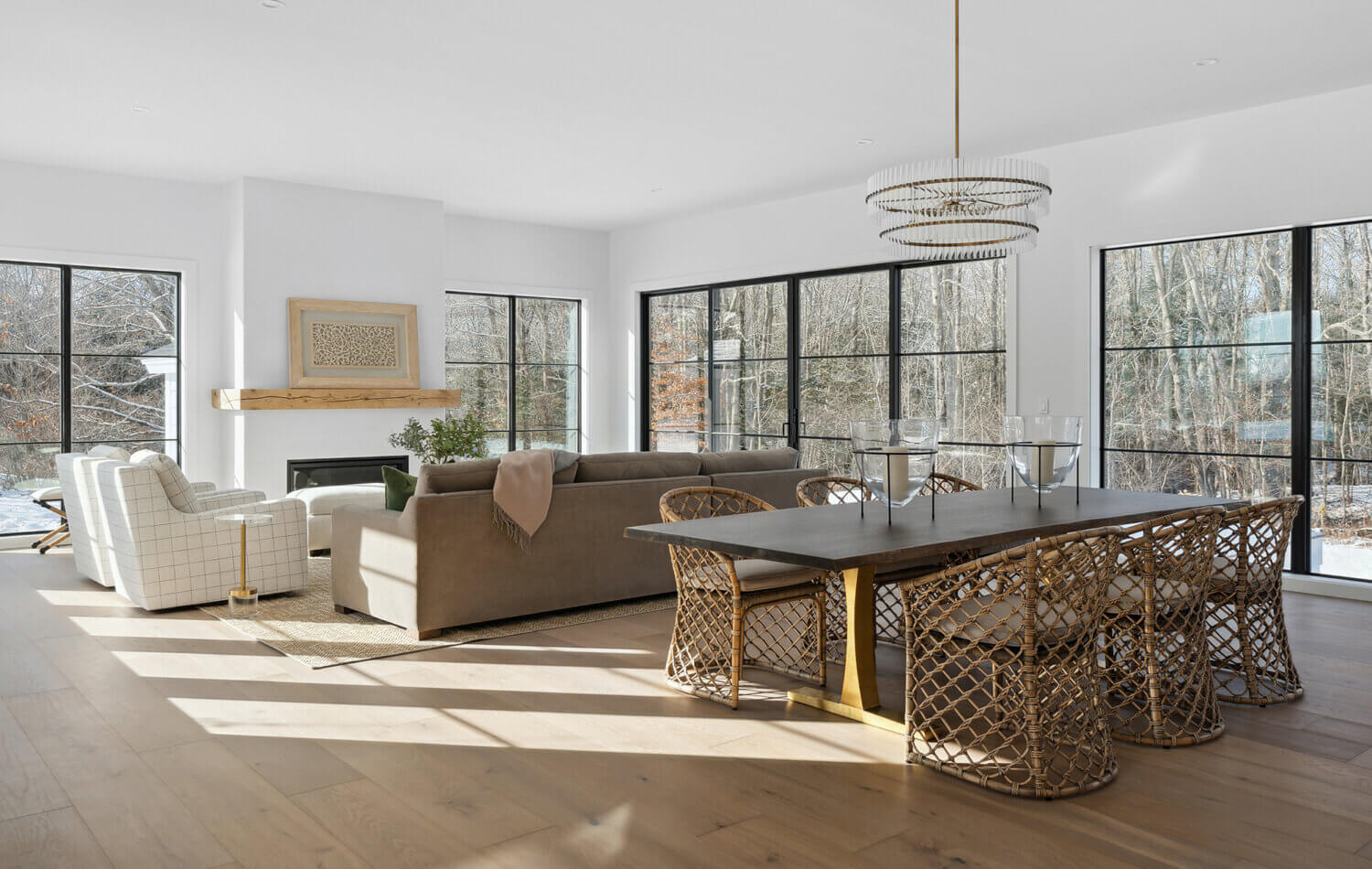 An open floor plan of the kitchen, dining room and living room in a modern farmhouse. This home features lots of large black framed windows with an amazing amount of natural light.