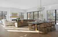 An open floor plan of the kitchen, dining room and living room in a modern farmhouse. This home features lots of large black framed windows with an amazing amount of natural light.