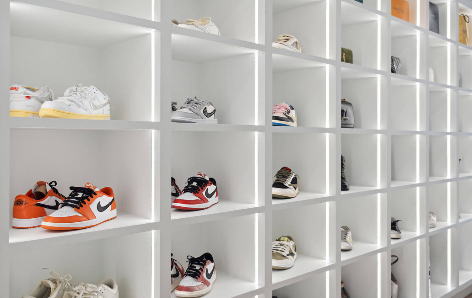 A luxury walk-in closet off the master bedroom with his and her storage. There is a full wall of open cubby storage for displaying shoes with integrated lighting to accent and create a store-like feel to the space.