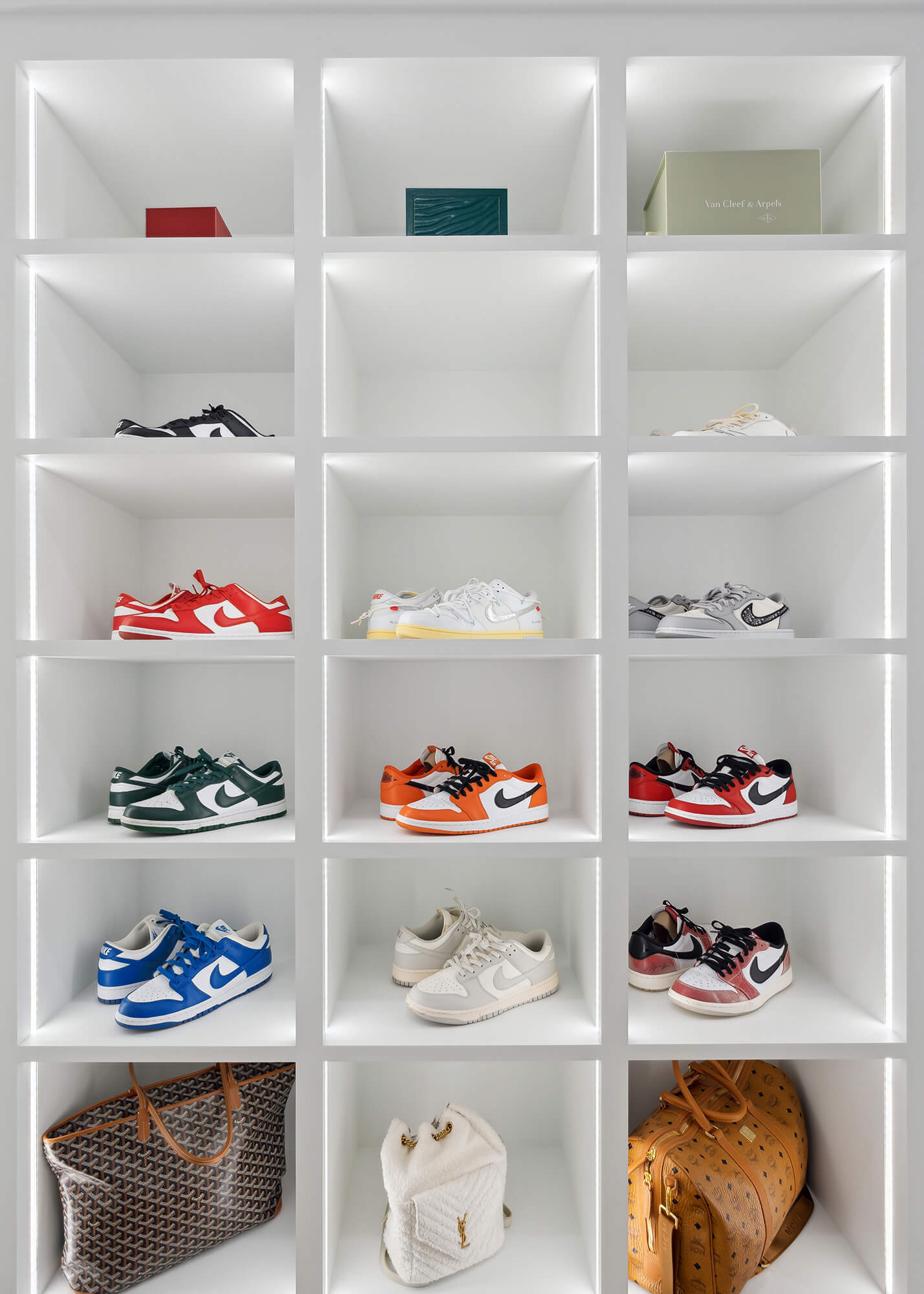 A luxury walk-in closet off the master bedroom with his and her storage. There is a full wall of open cubby storage for displaying shoes with integrated lighting to accent and create a store-like feel to the space.