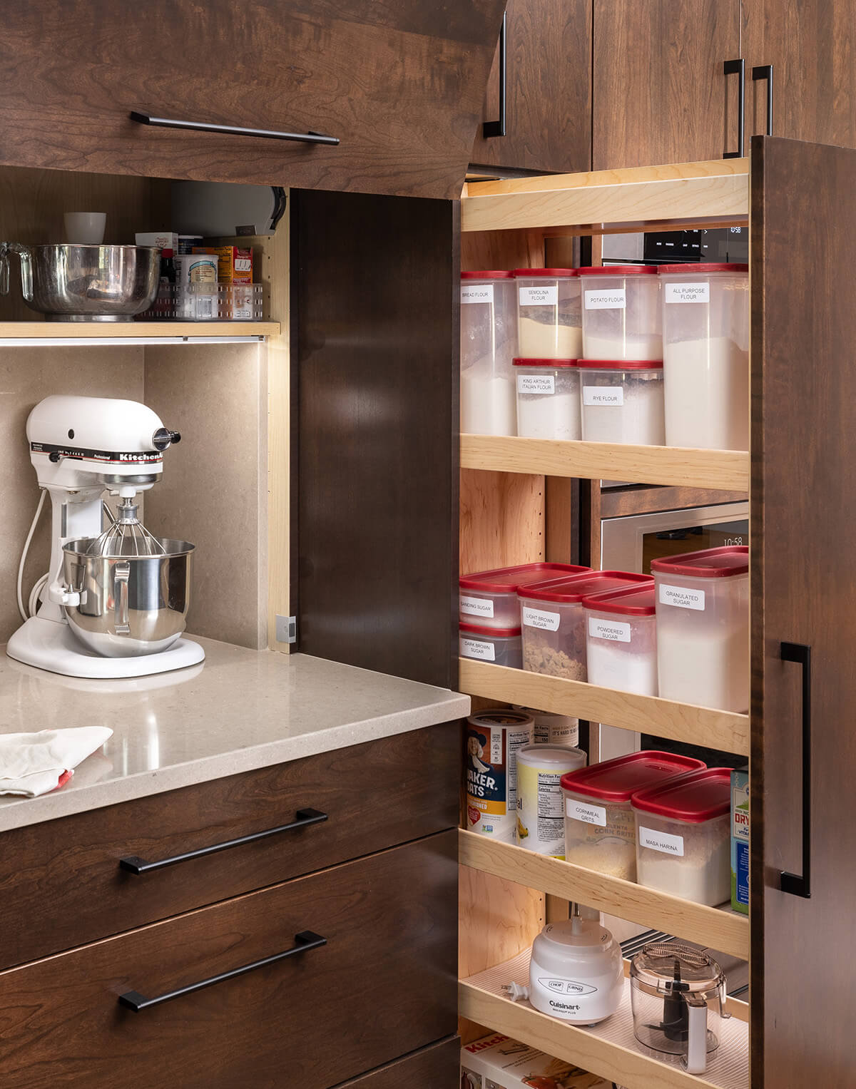 A tall pantry pull-out cabinet that houses lots of pantry supplies for the baking station area for supplies like flour, sugar, vanilla, nutmeg, etc.