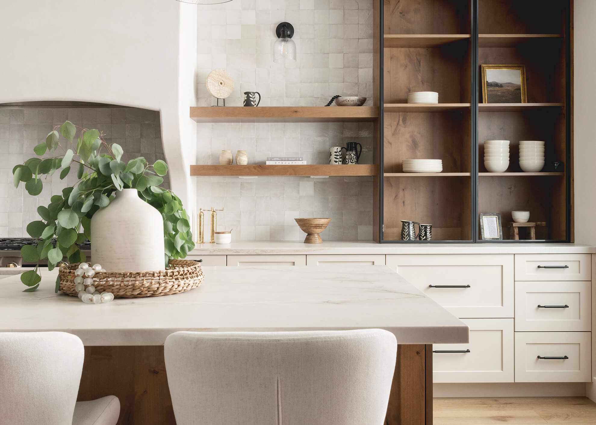 A modern Mediterranean style kitchen design with white painted cabinets and natural, light stained knotty alder with black metal cabinet doors.