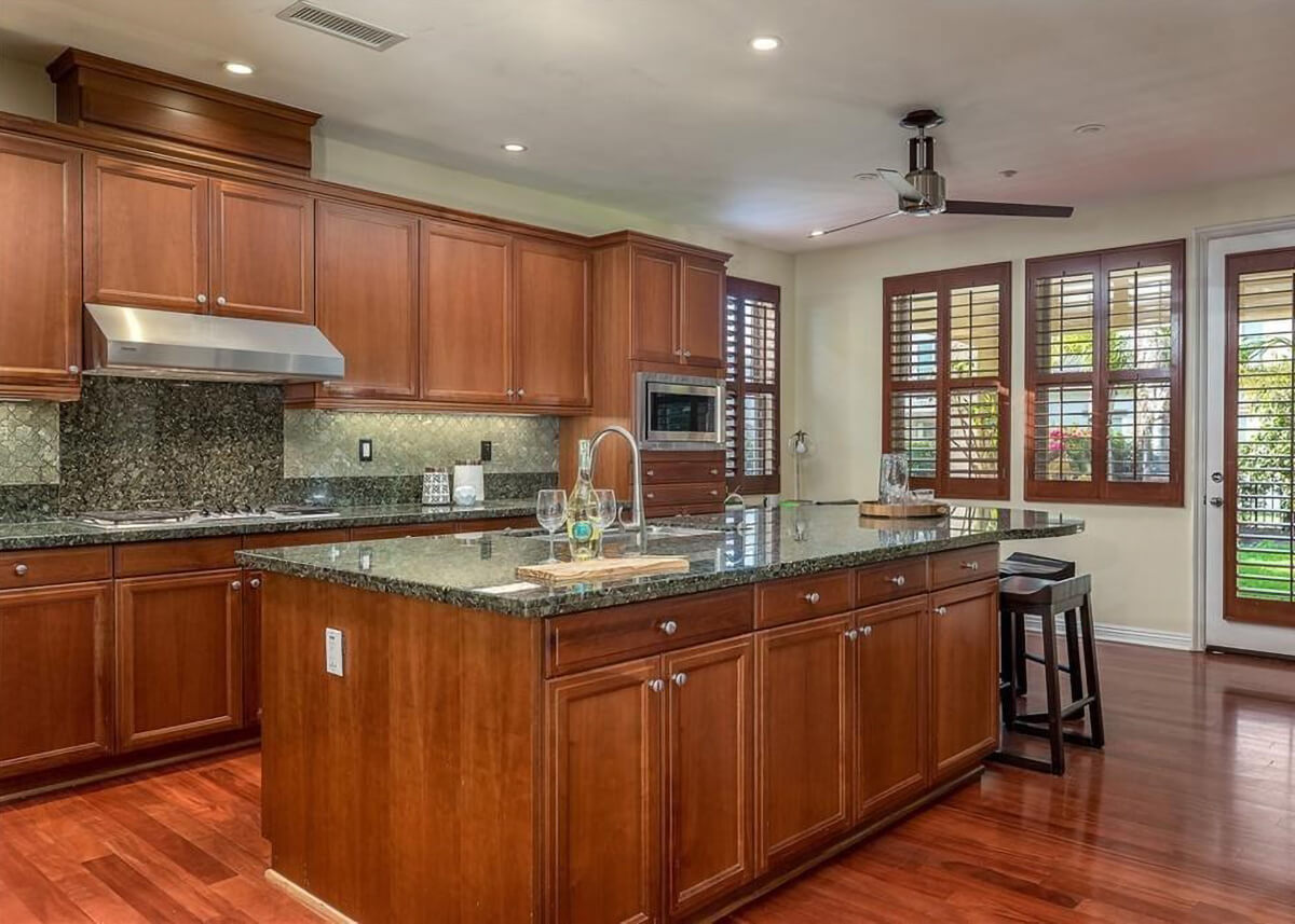 A before picture of the kitchen showing the lack of sun light and red stained cabinets that did not fit the style of the homeowners.