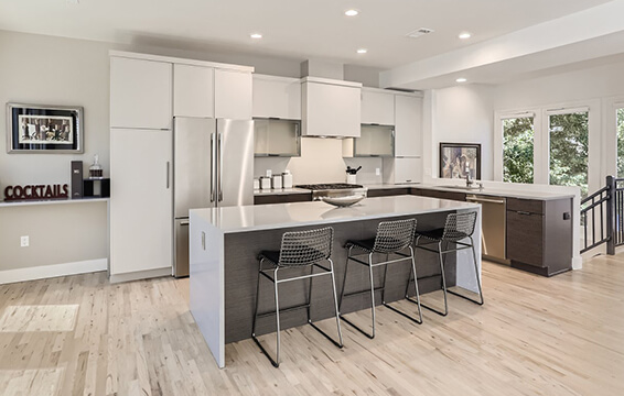 A modern white and gray kitchen with contemporary shale cabinets contrasted by off-whit painted cabinets with a modern skinny shaker door style.