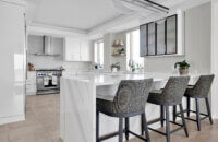 A modern style kitchen with bright, glossy white cabinets and bold black accents.