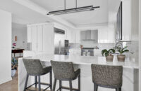 A modern style kitchen with bright, glossy white cabinets and bold black accents.