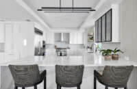 A modern style kitchen with bright, glossy white cabinets and bold black accents.