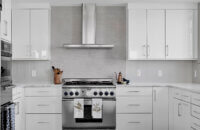 A modern style kitchen with bright, glossy white cabinets and bold black accents.