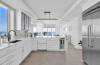 A modern style kitchen with bright, glossy white cabinets and bold black accents.