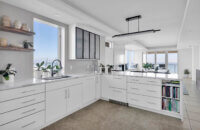 A modern style kitchen with bright, glossy white cabinets and bold black accents.