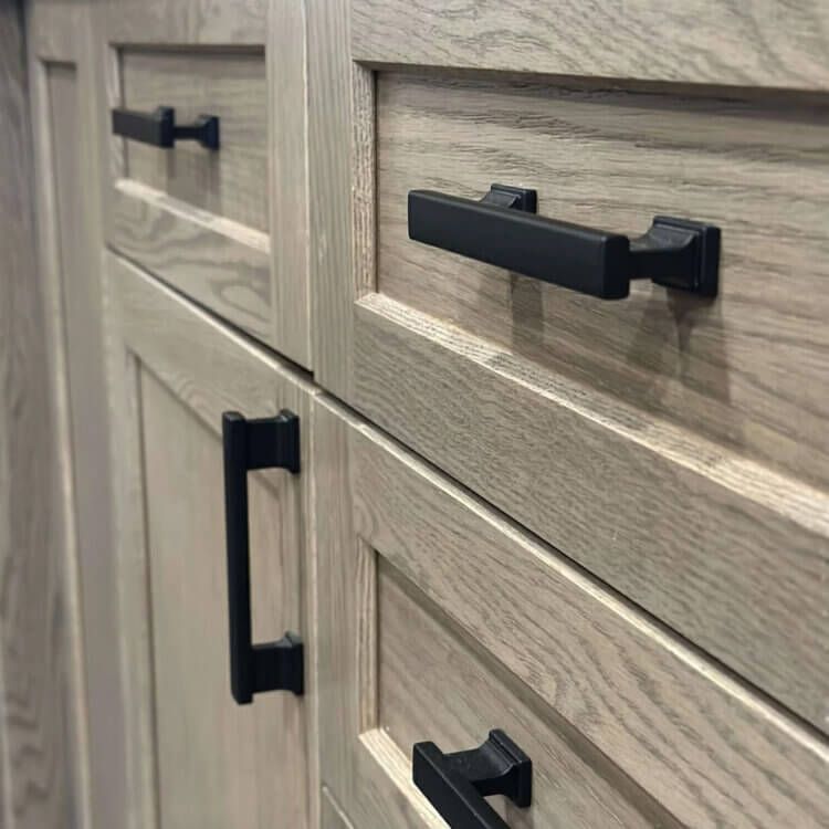 Dura Supreme Cabinetry's Hudson shaker door style in a light gray-brown on stain on Red Oak with black hardware.