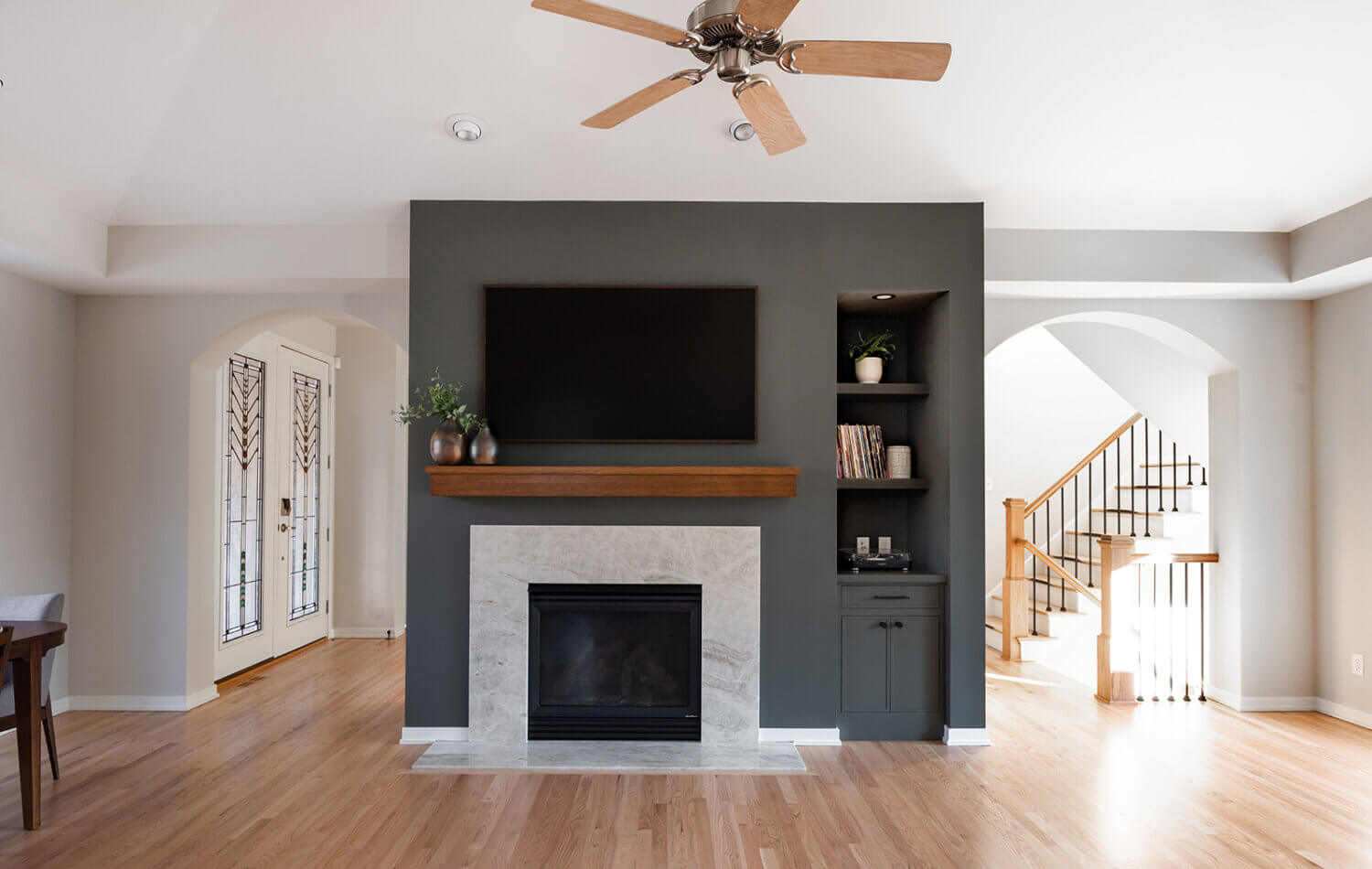 A divider wall between the kitchen and living space features a dark green color drenched fireplace with green built-in cabinets.