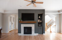 A divider wall between the kitchen and living space features a dark green color drenched fireplace with green built-in cabinets.