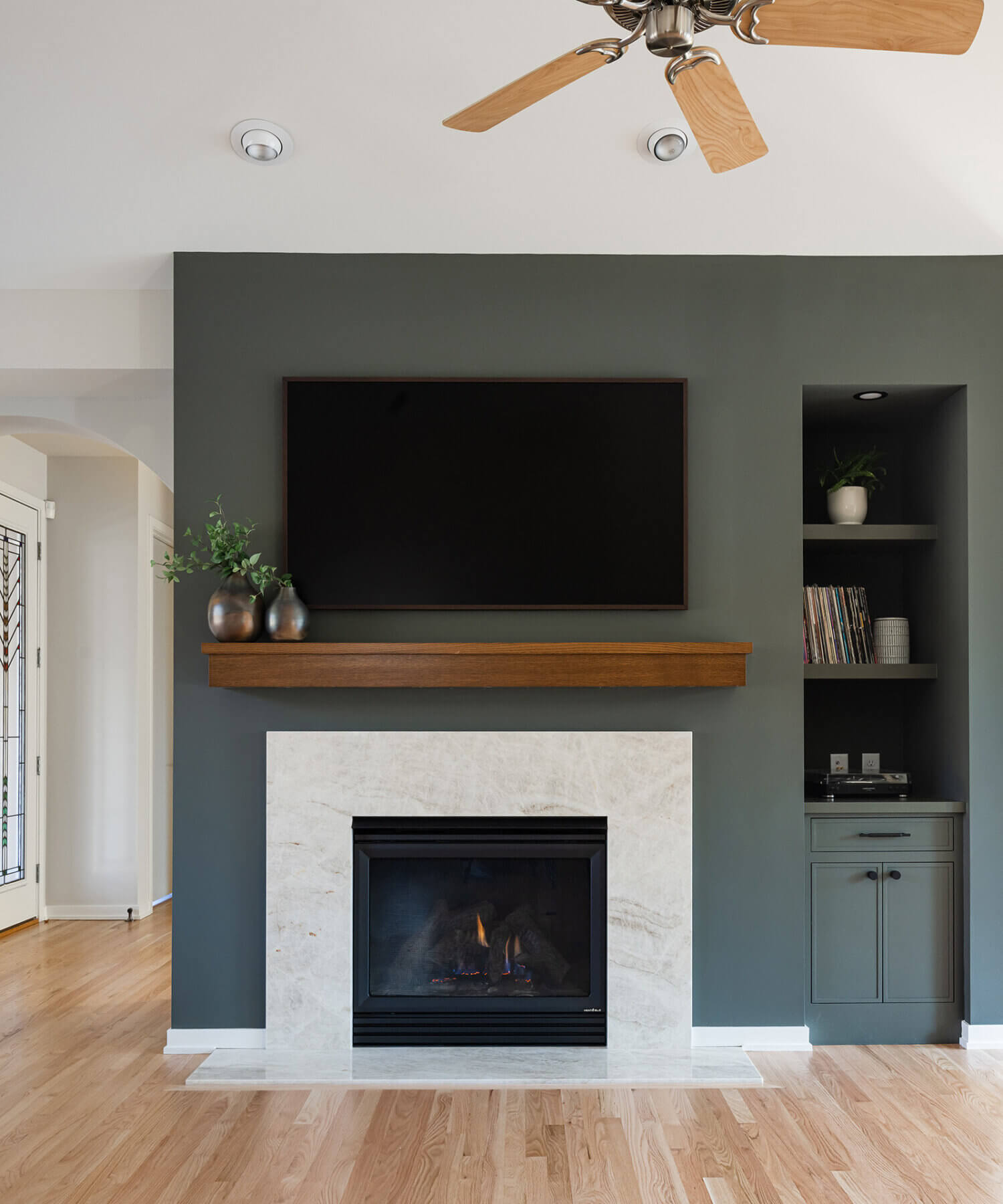 A divider wall between the kitchen and living space features a dark green color drenched fireplace with green built-in cabinets.