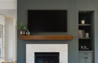 A divider wall between the kitchen and living space features a dark green color drenched fireplace with green built-in cabinets.