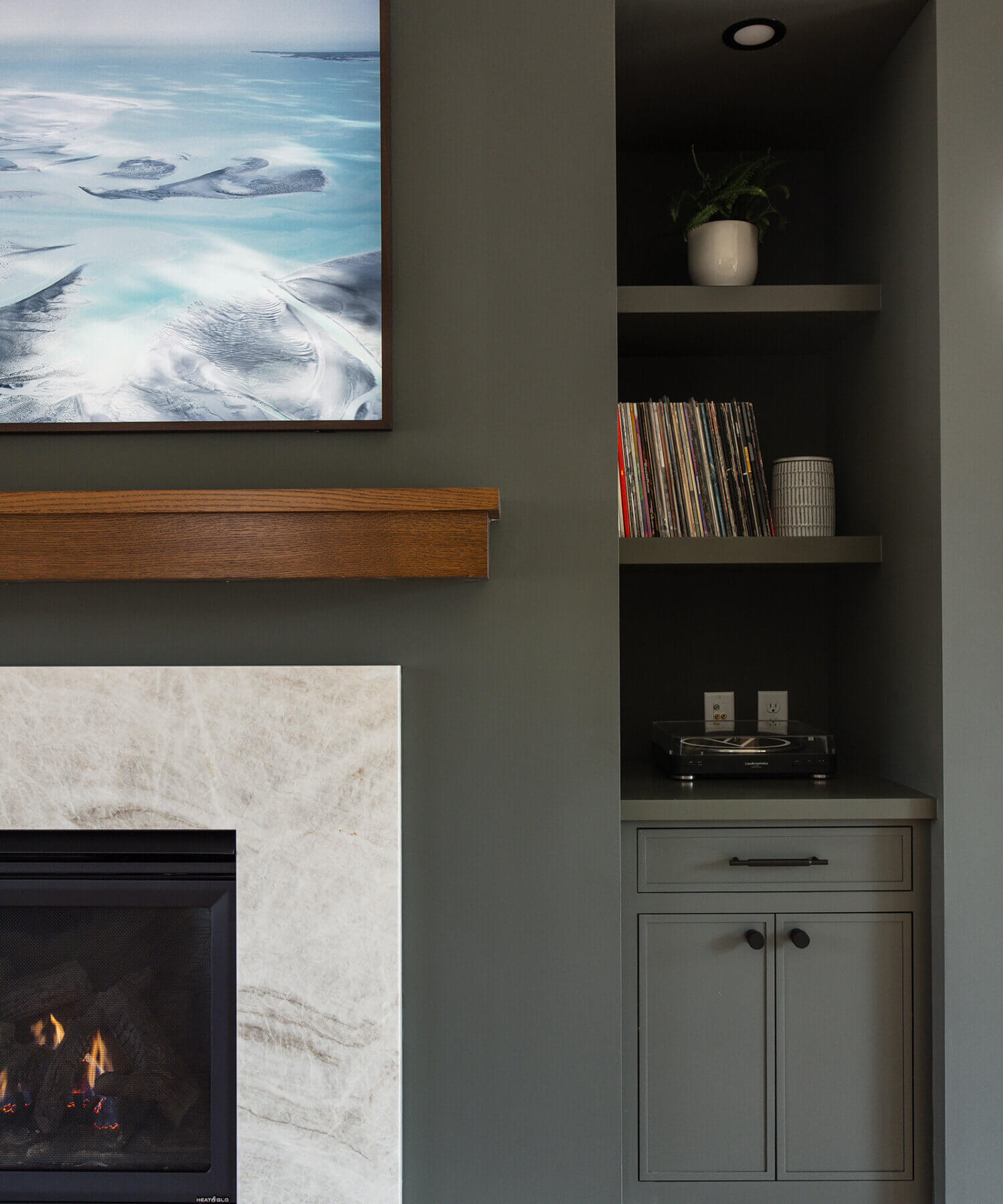 A divider wall between the kitchen and living space features a dark green color drenched fireplace with green built-in cabinets.