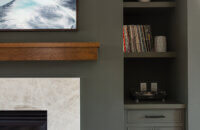 A divider wall between the kitchen and living space features a dark green color drenched fireplace with green built-in cabinets.