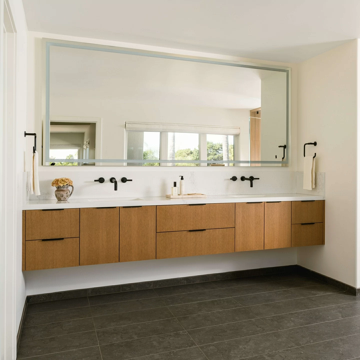 This modern master bathroom features a long, double sink vanity with wall hung, floating Quarter-Sawn White oak cabinets.