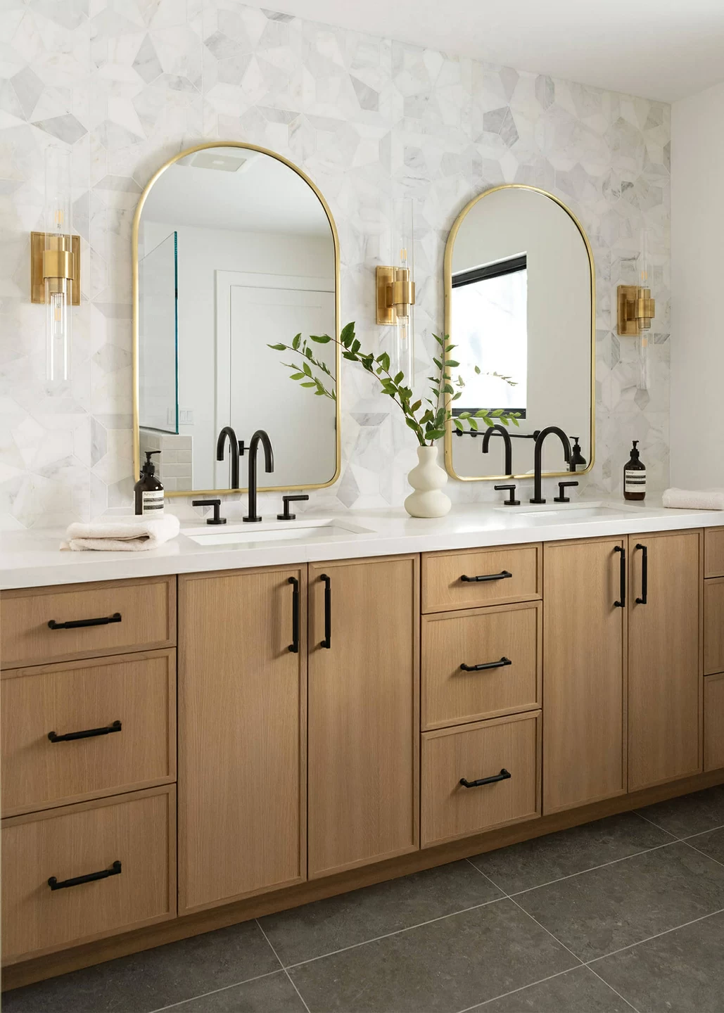 A luxurious and modern double sink vanity featuring skinny shaker cabinet doors in a warm, light stained finish on Quartersawn white oak.