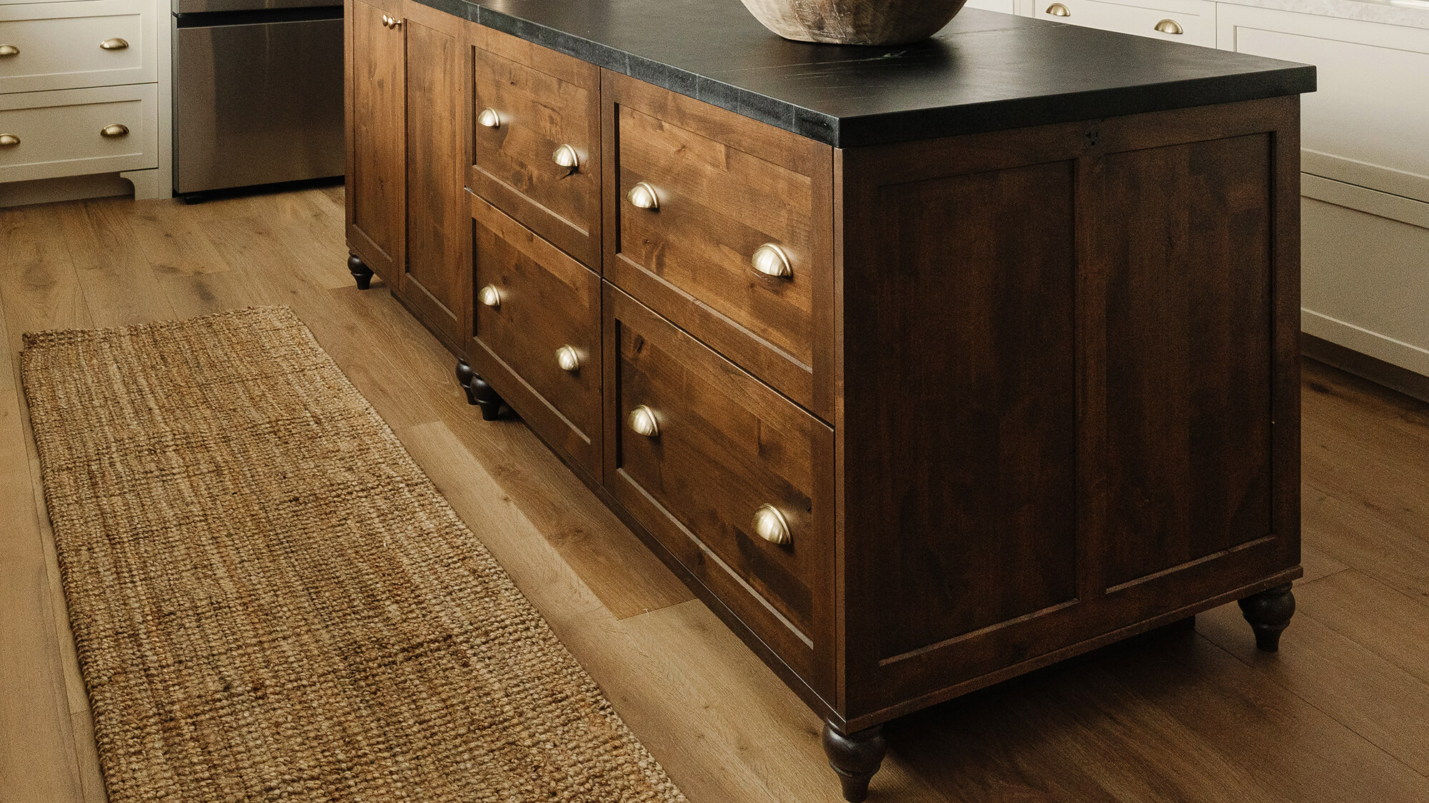 A close up of a true brown stained knotty alder kitchen island with a honed countertop and natural, organic decor and details.